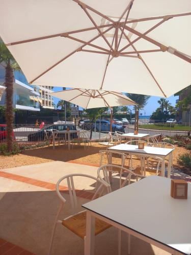 un gruppo di tavoli e sedie con ombrelloni bianchi di Terra Aurea Aparthotel a Salou