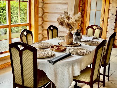 a dining room table with a white table cloth and chairs at Eco-House Ainaži in Ainaži