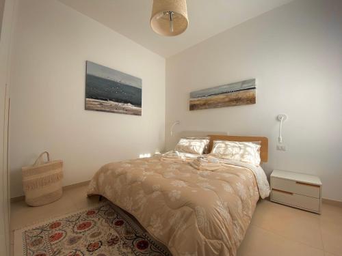 a bedroom with a bed and a nightstand and two pictures at Villetta frontemare Torre Suda Salento in Torre Suda