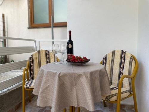 a table with a bottle of wine and a bowl of fruit at Jelić apartmani in Sutomore