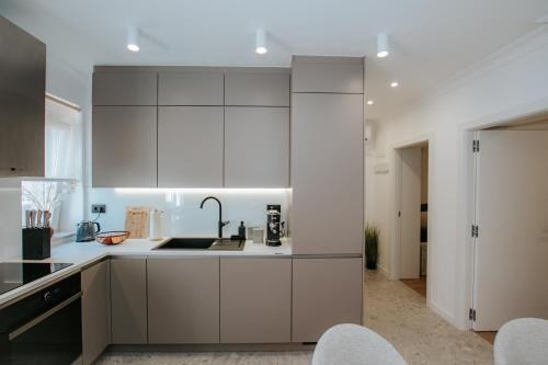 Apartment Datala في مارينا: مطبخ مع دواليب بيضاء ومغسلة