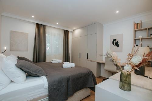 Apartment Datala في مارينا: غرفة نوم مع سرير و مزهرية من الزهور على طاولة