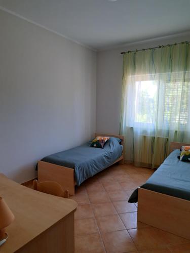 1 dormitorio con 2 camas y ventana en La casa di mezzo-affitti brevi-zona ospedali en Busso