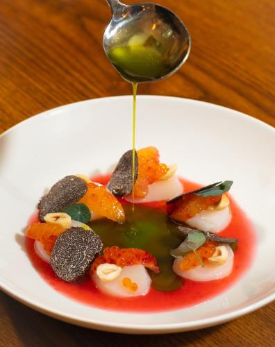 a spoon is drizzling sauce onto a plate of food at McGettigan's Townhouse - Olives & Figs Bistro in Dublin