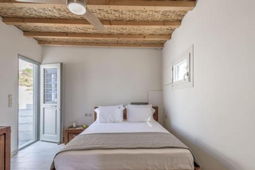 Un dormitorio con una cama con paredes blancas y techos de madera. en Casa del Mar Milos, en Kástron