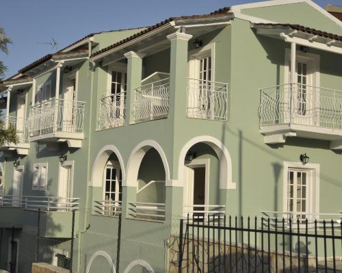 a green building with white balconies and a fence at Spiros Athinaios Apartment's in Dassia