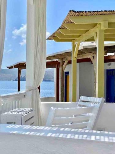 two white chairs sitting on a balcony with the ocean at Casa del Mar Milos in Areti