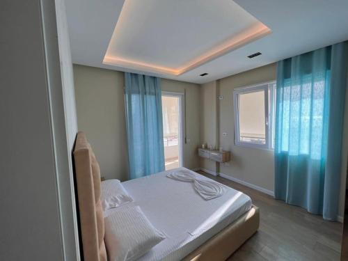 - une chambre avec un lit dans une pièce dotée de rideaux bleus dans l'établissement Soleil Apartment with sunbed & umbrella, à Vlorë