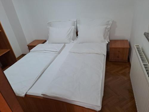 a bed with white sheets and pillows in a room at Eko Eko in Rijeka