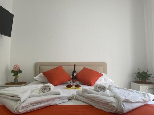 a bed with white sheets and orange pillows at Jelić apartmani in Sutomore