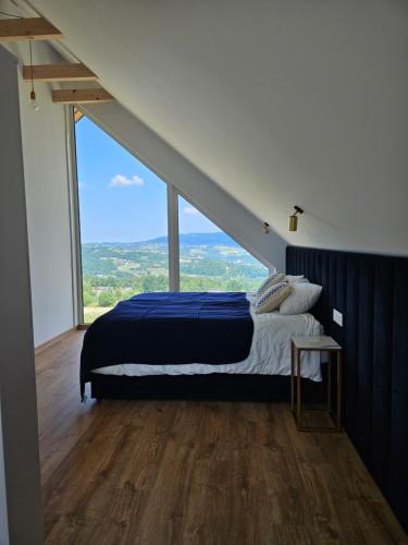 een slaapkamer met een bed en een groot raam bij Lipowe Apartmenty in Limanowa