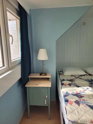 ein Schlafzimmer mit einem Bett und einem Tisch mit einer Lampe in der Unterkunft Cosy one-bedroom apartment in De Haan in De Haan