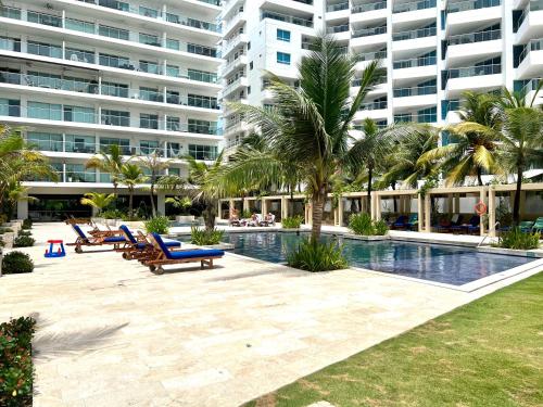 un complejo con una piscina con sillas y palmeras y un gran edificio en Frente al mar Morros Epic 323, en Cartagena de Indias