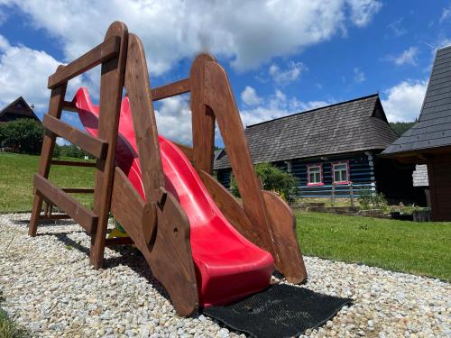 a playground with a red slide in front of a house at Chata Dolina v Bachledke in Ždiar