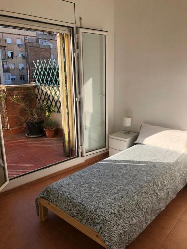 1 dormitorio con cama y vistas a un balcón en Ático en Gràcia, en Barcelona