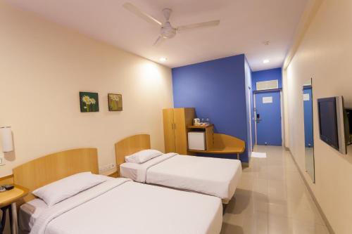 a bedroom with two beds and a blue wall at Ginger Nashik in Nashik