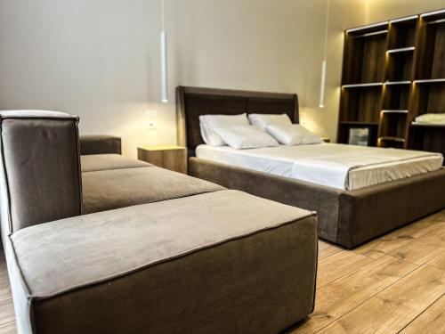 a bedroom with two beds and a ottoman at ALEXANDER Rooms & Apartments in Durrës