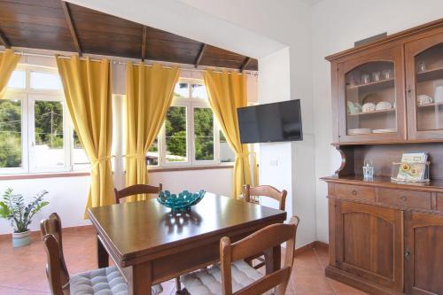 une salle à manger avec une table en bois et des rideaux jaunes dans l'établissement Simonelli Apartments, à Ischia