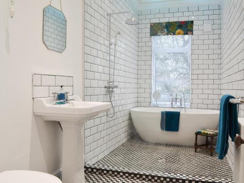 a white bathroom with a sink and a bath tub at The Manse in Coxhoe