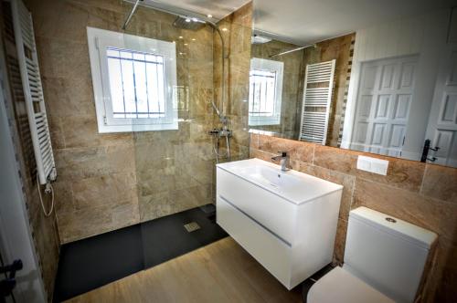 ein Badezimmer mit einem Waschbecken, einem WC und einem Spiegel in der Unterkunft Leng Vacation Home in Calonge