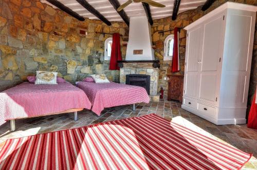 two beds in a room with a stone wall at Leng Vacation Home in Calonge