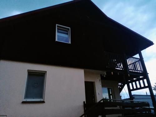 uma casa com um telhado preto e uma varanda em Apartament Charzykowy em Charzykowy