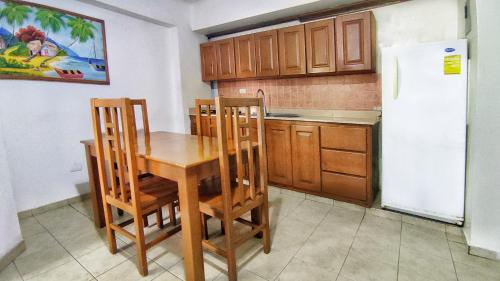 cocina con mesa, sillas y nevera en Acuarium Suite Resort, en Santo Domingo
