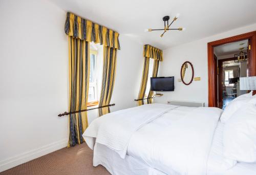 a bedroom with a white bed and a television at CARLTON COURT - MAYFAIR in London