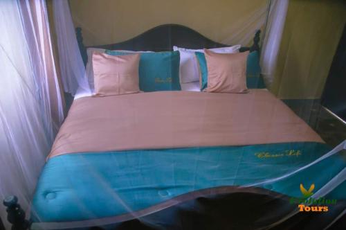 Bett mit rosa und blauer Bettwäsche und Kissen in der Unterkunft Starnford Hotel in Njara