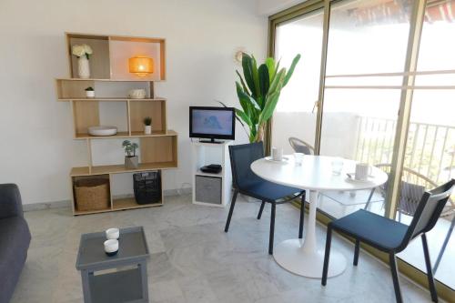 a living room with a table and chairs and a tv at Charming T2 Eden Park with swimming pool private parking in Juan-les-Pins