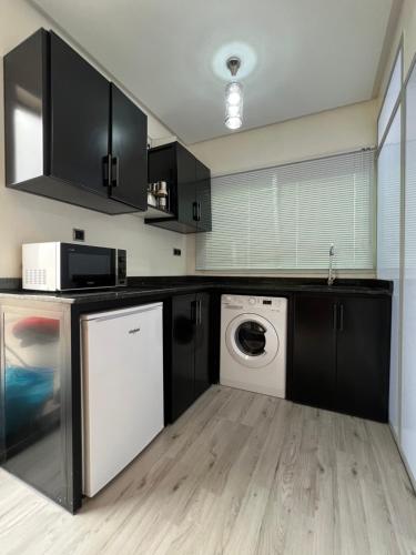 uma cozinha com armários pretos e uma máquina de lavar e secar roupa em Cozy luxurious studio with high end amenities em Fez