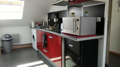 une petite cuisine avec des placards rouges et un four micro-ondes dans l'établissement Studio proche centre-ville et gare, à Amiens