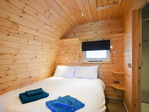 a bed in a wooden room with two towels on it at Barcud Coch - Uk44539 in Hirnant