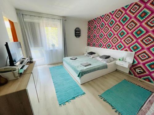 1 dormitorio con cama y pared de color rosa en Joy Apartman, en Zalakaros