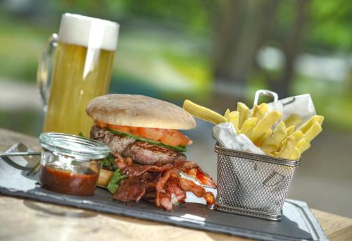 a tray with a sandwich and fries and a glass of beer at Nells Park Hotel in Trier
