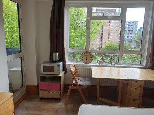 a kitchen with a desk and a window with a microwave at Rowland Hill House in London