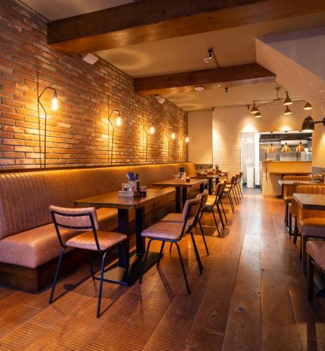 a restaurant with wooden tables and chairs and a brick wall at McGettigan's Townhouse - Olives & Figs Bistro in Dublin