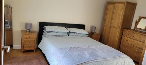 a bedroom with a bed with two dressers and two lamps at Adorable 1 bed log cabin with log burner in Frome