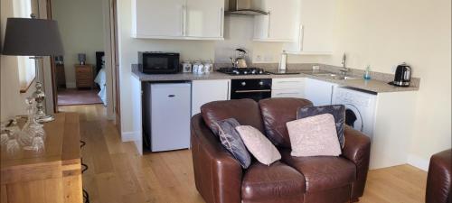 a living room with a leather couch in a kitchen at Adorable 1 bed log cabin with log burner in Frome