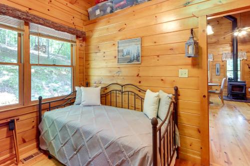 a bedroom with a bed in a room with wooden walls at Ellijay Cabin with Deck and Hot Tub! in Ellijay