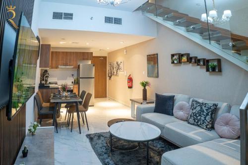 un soggiorno e una cucina con divano e tavolo di Blackforest 2BR Duplex at Masdar Oasis a Abu Dhabi