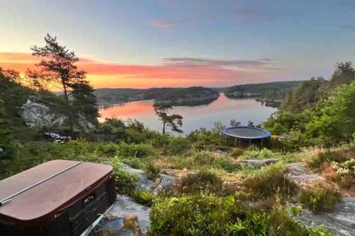 - une vue sur une rivière au coucher du soleil avec un bateau dans l'établissement Cottage, boat, spa, private dock, Lillesand, à Lillesand