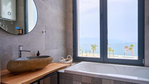 a bathroom with a sink and a tub with a window at Azar Luxury Suites in Vlorë