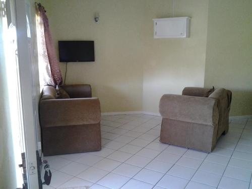 a living room with two chairs and a tv at Aupic Paradise in Vieux Fort