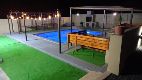 un patio con panchina e piscina di notte di The Success Guest House a Standerton