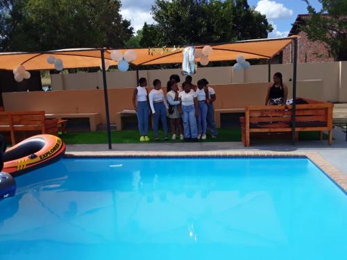 un gruppo di persone che si trovano di fronte a una piscina di The Success Guest House a Standerton
