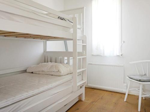 a white bunk bed in a white room with a chair at Modern Beach Cottage in Tofta, Gotland in Gnisvärd