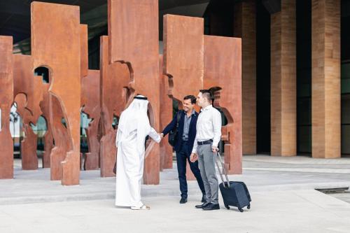 a group of three men shaking hands in front of a sculpture at Holiday Inn & Suites - Dubai Science Park by IHG in Dubai