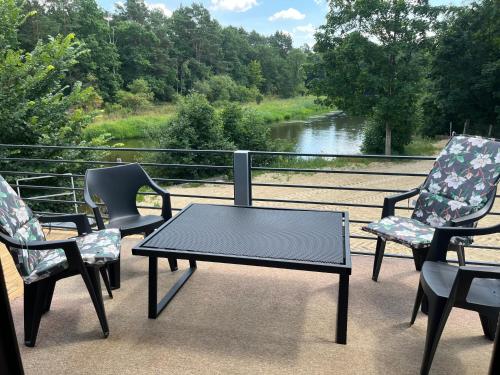a table and chairs on a balcony with a view of a river at Domek Survivalowy w Spale in Spała