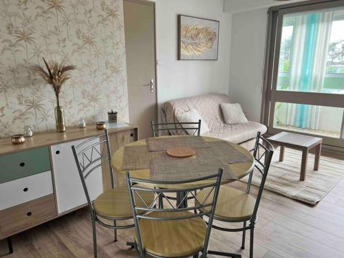 un salon avec une table et des chaises et une cuisine dans l'établissement Appartement à 100 m de la plage avec parking, à Saint-Hilaire-de-Riez